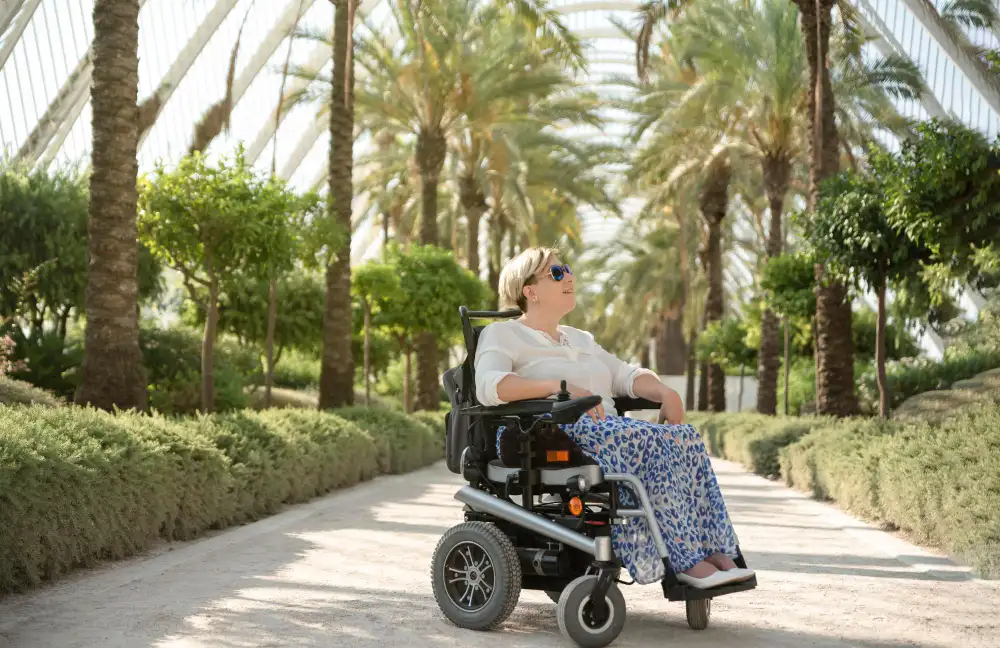 mujer dando un paseo en una silla de ruedas electrica bajo el sol de la tarde